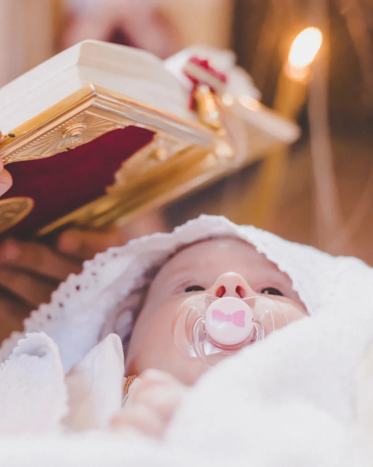 Bebé vestido de blanco durante su bautizo en la iglesia