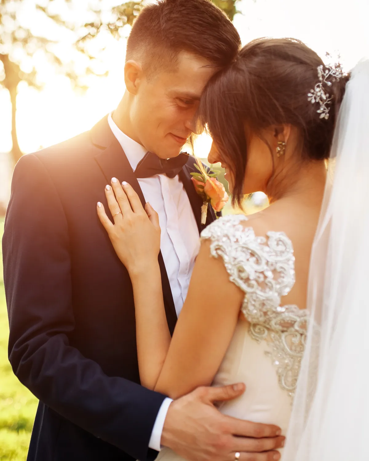 Novios abrazados frente con frente al atardecer el día de su boda