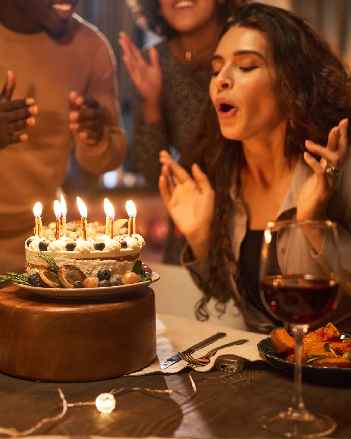 Mujer soplando las velas de su pastel de cumpleaños junto a sus amigos